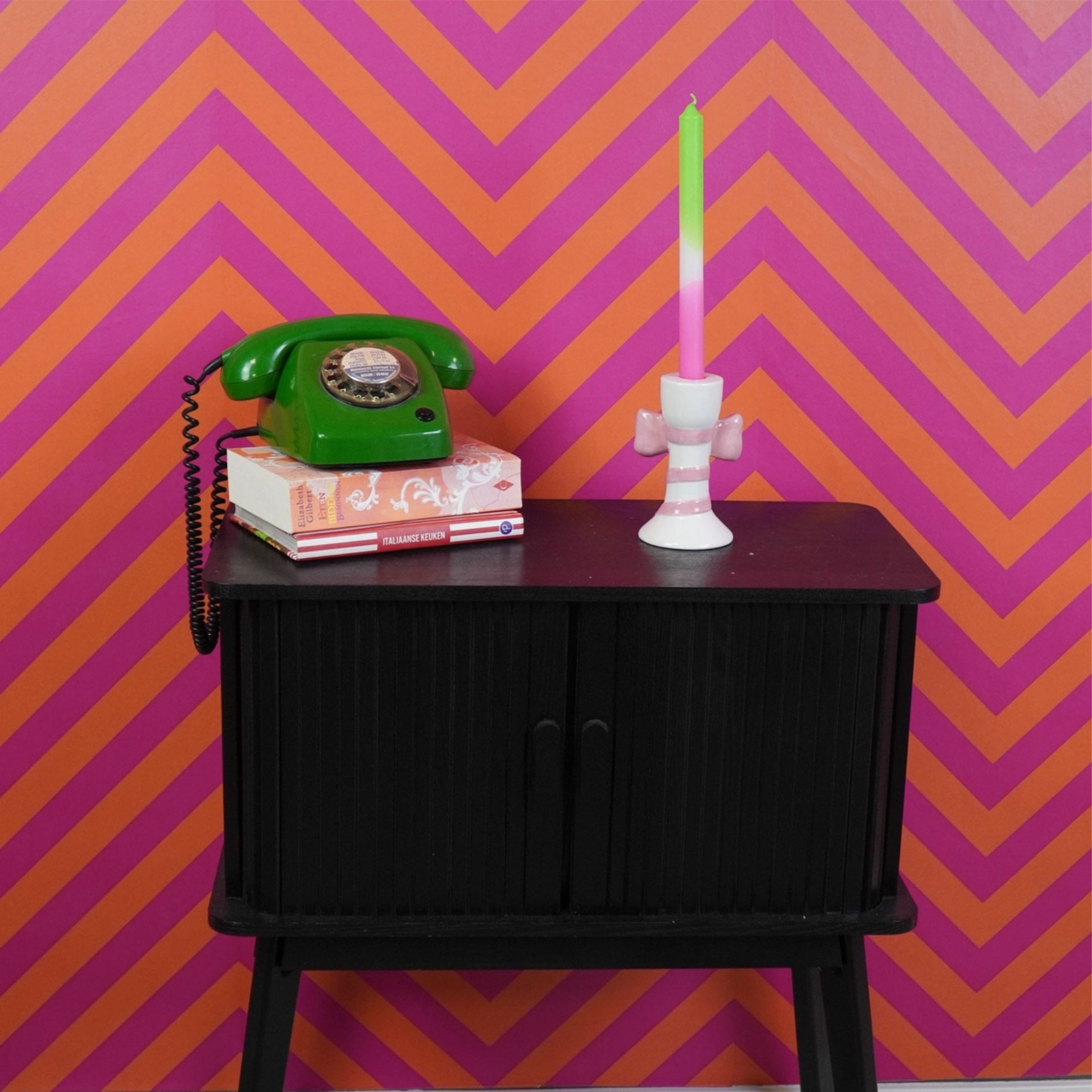 Kaunis kynttilänjalka jossa valkoisella pohjalla vaaleanpunainen rusetti nauhoineen